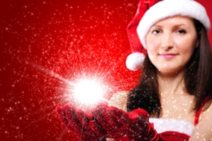 Girl with Santa hat holding hands out with red gloves and a globe of star light in them