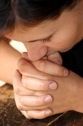 Woman praying over clasped hands